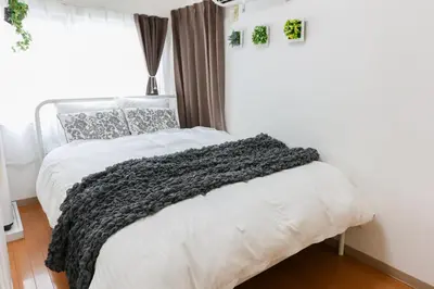 a bedroom with a bed with a gray blanket on it at \u30cf\u30a4\u30af\u30ec\u30b9\u30c8\u4e2d\u91ce202 in Tokyo