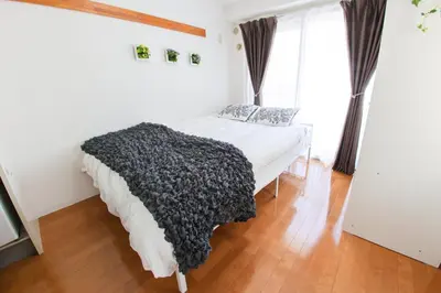 a bedroom with a bed with a black blanket at \u30cf\u30a4\u30af\u30ec\u30b9\u30c8\u4e2d\u91ce102 in Tokyo