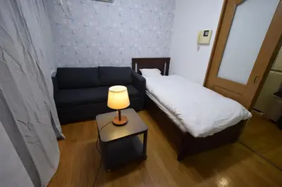 a room with a bed and a couch and a lamp at \u6587\u4eac\u533a\u8c4a\u5cf6\u533a\u5357\u5927\u585a in Tokyo