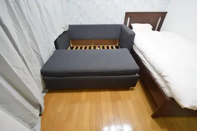 a blue couch sitting next to a bed at \u6587\u4eac\u533a\u8c4a\u5cf6\u533a\u5357\u5927\u585a in Tokyo