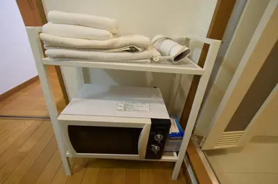 a shelf with a microwave and towels on it at \u6587\u4eac\u533a\u8c4a\u5cf6\u533a\u5357\u5927\u585a in Tokyo