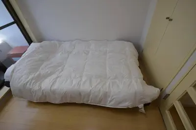 a bed with a white comforter in a room at \u6771\u4eac\u30e1\u30c8\u30ed\u4e38\u30ce\u5185\u7dda\u5f92\u6b691\u5206 in Tokyo