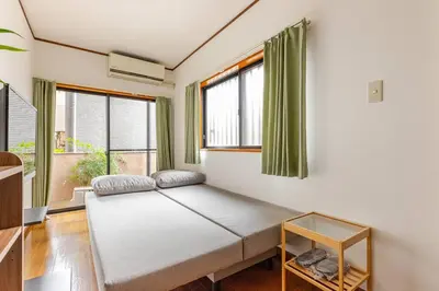 a bed in a room with windows and a tv at kensui house in Tokyo