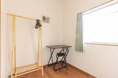 a table and a stool in a room with a window at kensui house in Tokyo