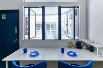 a white table with blue chairs and a window at Kaikai House - Art, Design & Family in Shibuya in Tokyo