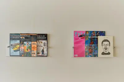 three magazines are hanging on a wall at Kaikai House - Art, Design & Family in Shibuya in Tokyo