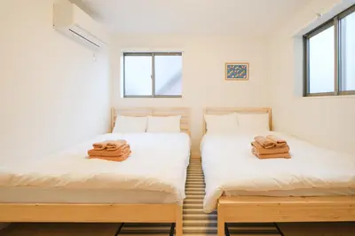 two twin beds in a room with windows at Mi-Villa SOMO in Tokyo