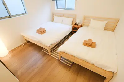 two twin beds in a room with wooden floors at Mi-Villa SOMO in Tokyo