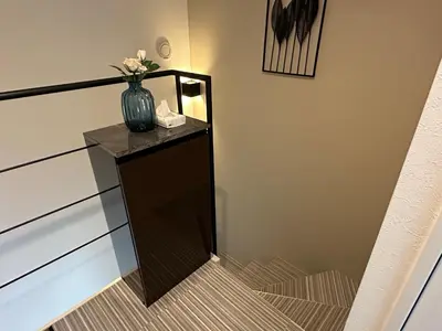 a stairway with a vase on a table with a staircase at COMMA HOUSE Shinjuku 11 in Tokyo