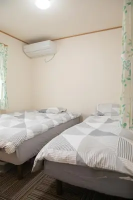 two beds sitting next to each other in a bedroom at \u30b9\u30ab\u30a4\u30c4\u30ea\u30fc\u524d\u62bc\u4e0a\u99c5\u65b0\u7bc9\u30f4\u30a3\u30e9\u7a7a\u6e2f\u76f4\u901a in Tokyo
