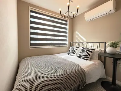 a bedroom with a bed with a window and a chandelier at COMMA HOUSE Shinjuku 13 in Tokyo