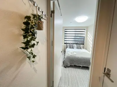 a bedroom with a bed and a plant on the wall at COMMA HOUSE Shinjuku 14 in Tokyo