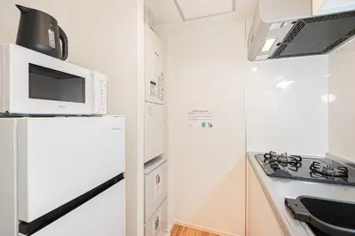 a small kitchen with a microwave and a refrigerator at Toggle\u30a2\u30d1\u30fc\u30c8\u83ca\u5ddd\u99c5\u304b\u3089\u5f92\u6b69 in Tokyo