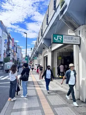 a group of people walking down a sidewalk outside a store at \u68ee\u4e0b\u99c52\u5206\u4e21\u56fd\u99c57\u5206Skytreeview401 in Tokyo