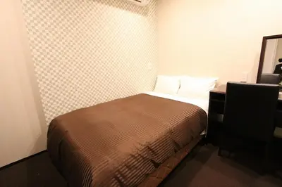 a small bedroom with a bed and a desk at HOTEL LiVEMAX Nihonbashi Hakozaki in Tokyo