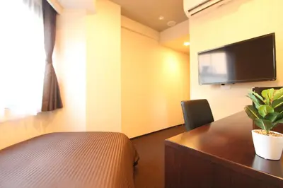 a room with a table and a tv on a wall at HOTEL LiVEMAX Nihonbashi Hakozaki in Tokyo