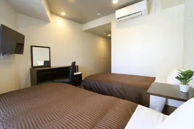 a hotel room with two beds and a desk at HOTEL LiVEMAX Nihonbashi Hakozaki in Tokyo