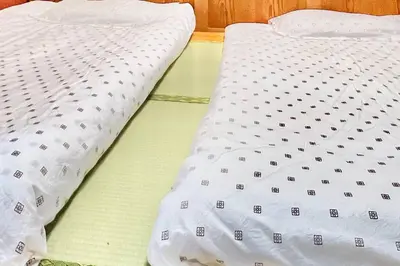 a bed with a white comforter on top of it at \u4e0a\u91ce\u516c\u56ed\u65c1\u65e5\u5f0f\u6c11\u5bbf3 in Tokyo