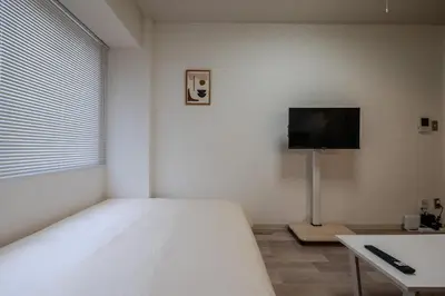 a bedroom with a bed and a tv on the wall at #8 -\u30a2\u30a4\u30e0\u30bf\u30a6\u30f3\u5357\u845b\u897f- Entire Unit in Tokyo
