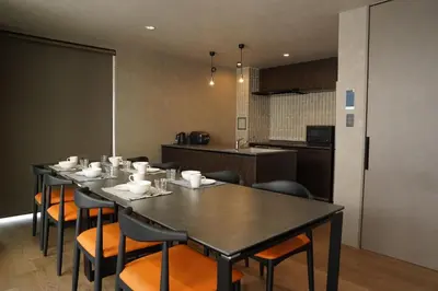 a dining room with a table and chairs and a kitchen at Musashi Condo Takadanobaba in Tokyo
