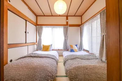 two beds in a small room with windows at Vivi Villa in Tokyo