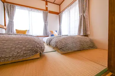 two beds in a bedroom with two windows at Vivi Villa in Tokyo