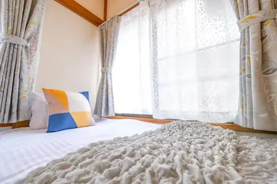 a bedroom with a white bed with a window at Vivi Villa in Tokyo