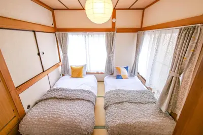 two beds in a small room with windows at Vivi Villa in Tokyo