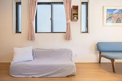 a bed in a room with a chair and windows at Four Trees Stay Yotsugi Skytree View in Tokyo