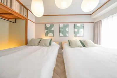 two beds in a room with white sheets at Midtown OIMACHI Hub in Tokyo