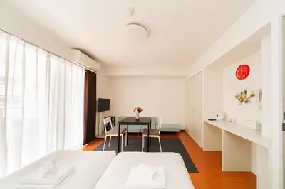 a white room with a table and a bed at Kamata Opus2 Apartment in Tokyo
