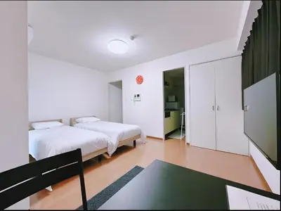 a bedroom with two beds and a tv in it at Kamata Opus2 Apartment in Tokyo