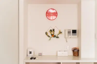 a clock on a white wall with a desk at Kamata Opus2 Apartment in Tokyo