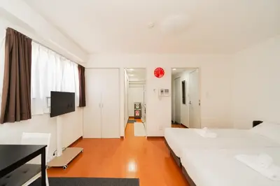 a white room with two beds and a tv at Kamata Opus2 Apartment in Tokyo