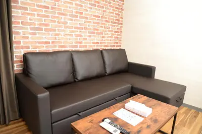 a leather couch with a coffee table and a brick wall at ACTResidence\u7b2c\u4e8c 4\u5ba41\u30d0\u30b9\u30eb\u30fc\u30e01\u30b7\u30e3\u30ef\u30fc3\u30c8\u30a4\u30ec in Tokyo