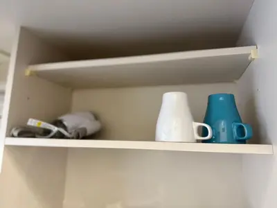 a shelf with cups and other items on it at Tokyo Shinjuku Waseda House\u65b0\u5bbf\u65e9\u7a32\u7530 in Tokyo