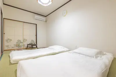 two beds in a room with a clock on the wall at Pachira\u65e5\u5f0f\u72ec\u680b2\u536b2\u6d74\u4e09\u4e2a\u623f\u95f4\u6c60\u888b\u7ad9\u5730\u94c17\u5206870 in Tokyo