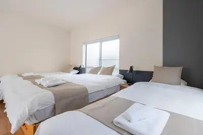 a room with three beds and a window at \u30a2\u30f3\u30c9\u30b9\u30c6\u30a4\u5927\u68ee\u897f2\u4e01\u76ee in Tokyo