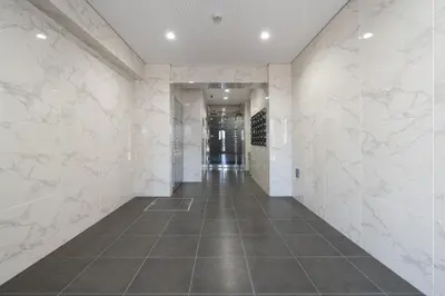 an empty hallway with white marble walls and a long corridor at GRAN PASEo\u9ad8\u5186\u5bfa\u5357 in Tokyo