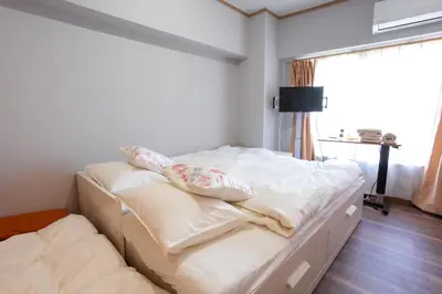 a white bed with pillows on it in a bedroom at Tokyo Yamate line Takadanobaba station one room partment in Tokyo