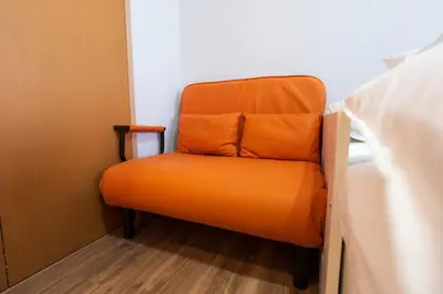 an orange chair in a room next to a bed at Tokyo Yamate line Takadanobaba station one room partment in Tokyo