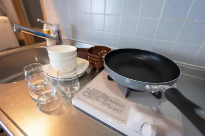 a pan sitting on a counter next to glasses at Tokyo Yamate line Takadanobaba station one room partment in Tokyo