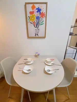 a white dining room table with white chairs and a painting at Mori house ookubobiru in Tokyo