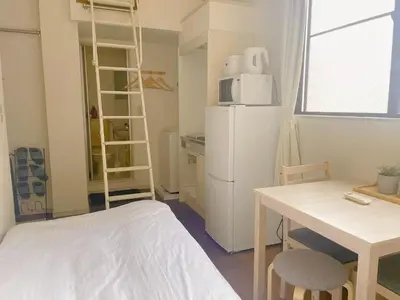 a small kitchen with a white refrigerator and a table at Mori house ookubobiru in Tokyo