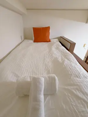 a white bed with two towels on it at Mori house ookubobiru in Tokyo