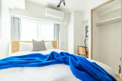 a bedroom with a blue blanket on a bed at Dash Living Asakusa East in Tokyo