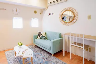 a living room with a blue couch and a mirror at Higashi-Shinjuku 904 in Tokyo