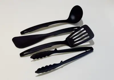 three black plastic utensils on a white background at Higashi-Shinjuku 904 in Tokyo