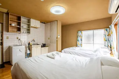 a room with two beds and a kitchen at \u30a2\u30f3\u30c9\u30b9\u30c6\u30a4\u6e0b\u8c37\u672c\u753a5\u4e01\u76ee2f in Tokyo