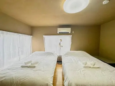 two beds in a room with white sheets at \u30a2\u30f3\u30c9\u30b9\u30c6\u30a4\u6e0b\u8c37\u672c\u753a5\u4e01\u76ee2f in Tokyo